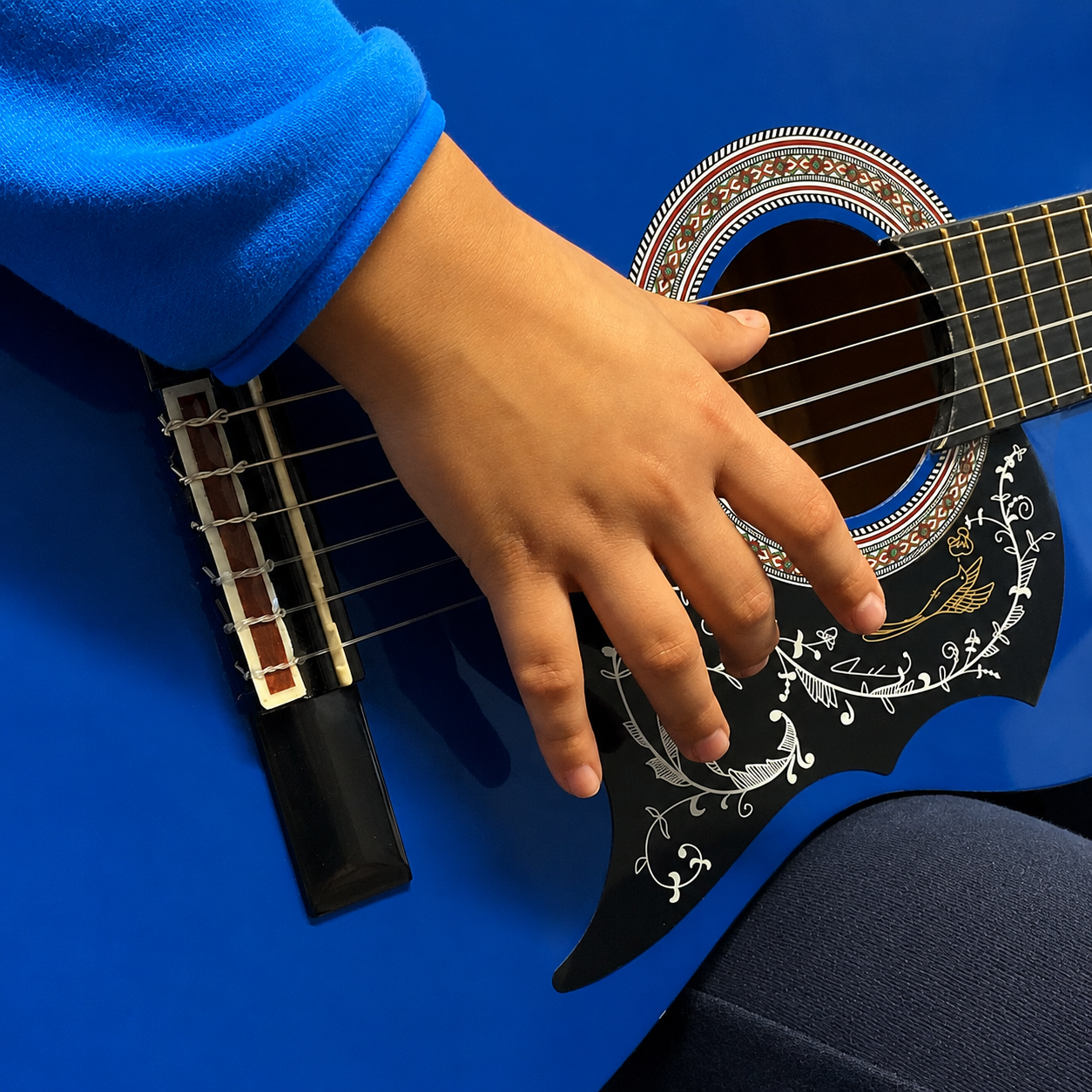 Mano di un allievo su una chitarra classica blu